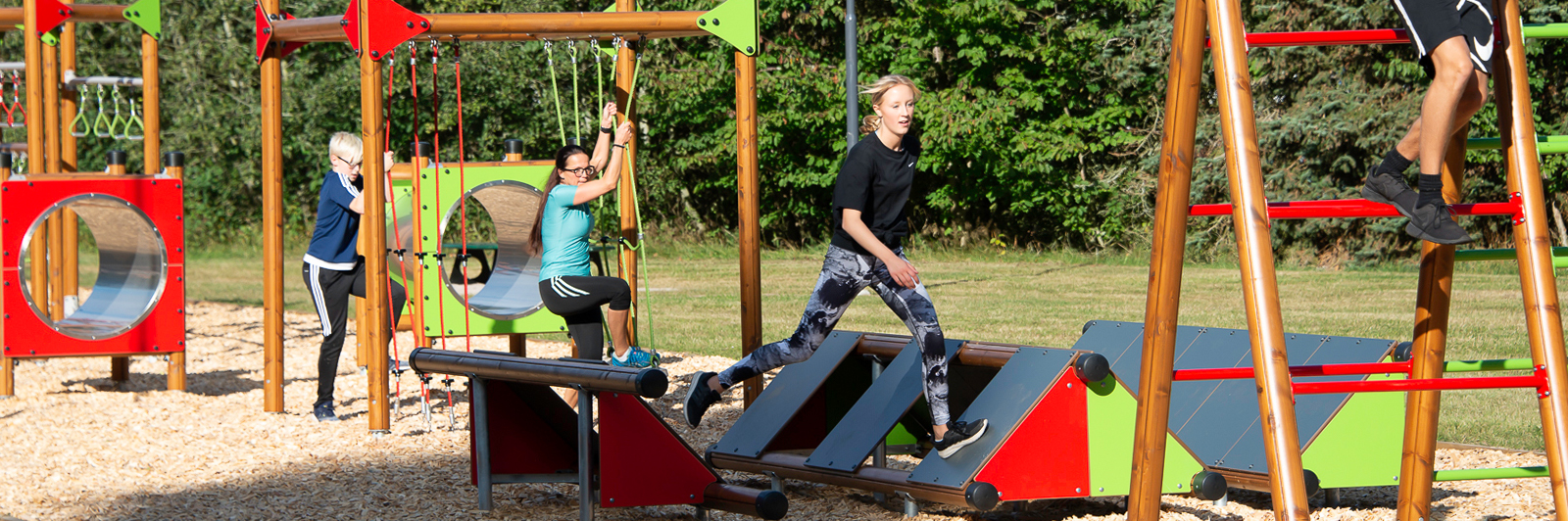 Multiple people making their way across a bright, red and green obstacle course